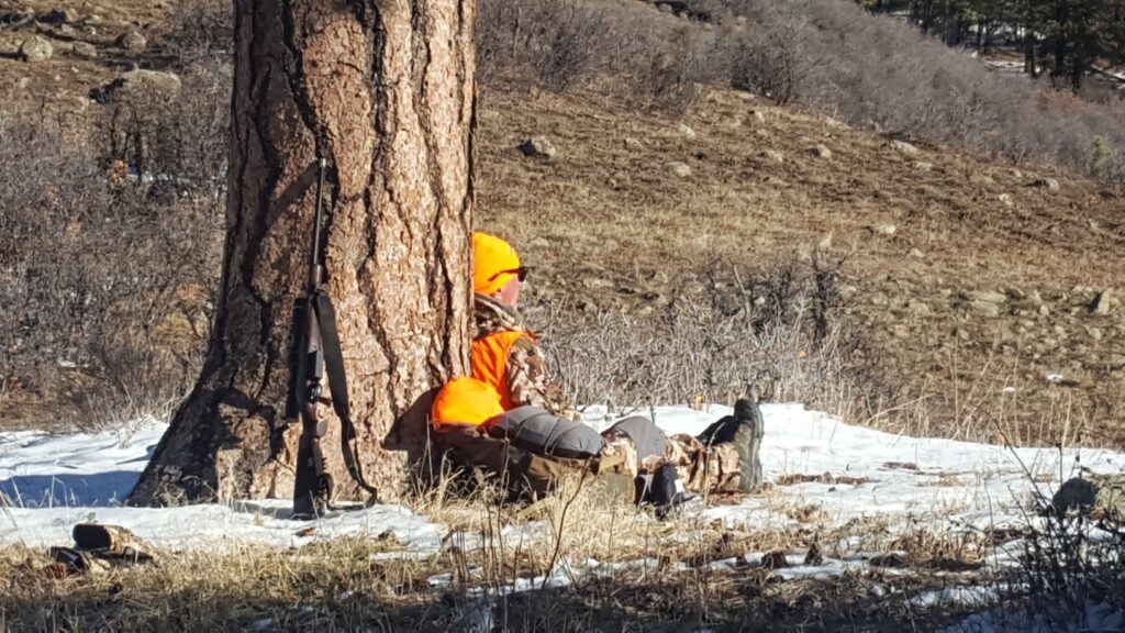 Hunting remote wilderness areas DIY - Hunter Gerald Gerwick sitting on the ground and leaning against a tree as he watches for elk.