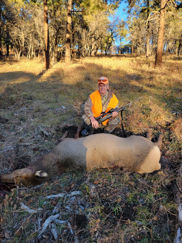 Rex McMahon with a kneeling behind a nice cow elk harvested with a rifle in Colorado