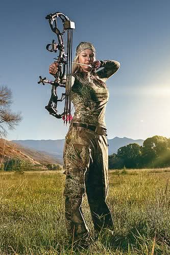 lady bowhunter in full camo about to draw her compound bow