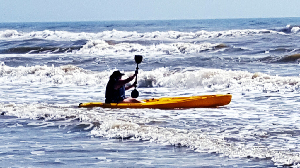 Kaysi Jo Garrett paddling a kayak in the surf.