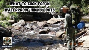 Essential Features of Waterproof Hiking Boots featured image showing Rex McMahon loaded down with his backpacking gear about to cross a mountain stream.